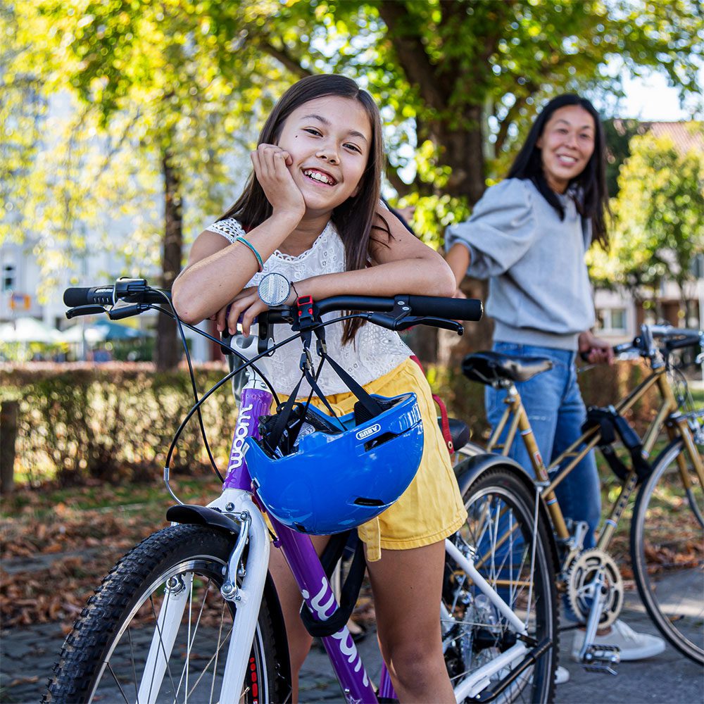 Eine Frau und ein Mädchen stehen mit Fahrrädern in einem Park unter einem Baum